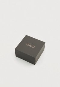 Cutie pătrată de carton maro închis, având pe suprafața superioară un logo „LIU JO” în relief aur roz. Textură simplă și netedă.