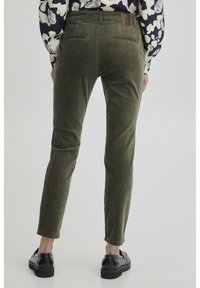 Pantaloni in velluto a coste verde oliva con vestibilità affusolata, dotati di tasche posteriori e una patch in pelle in vita, mostrati dal retro.