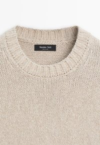Béžový pletený svetr s kulatým výstřihem, žebrovaným límcem a viditelnou štítkem „Massimo Dutti“ přišitým uvnitř výstřihu.