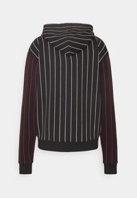 Musta huppari, jossa pystysuorat valkoiset ja punaiset raidat, kiristysnyörillä varustettu huppu ja resorireunaiset hihat. Pehmeä kangas ja rento istuvuus.