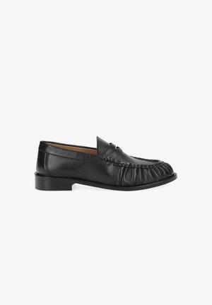 Mocassin en cuir noir à enfiler avec détails cousus et petit talon, vue de côté sur fond blanc.