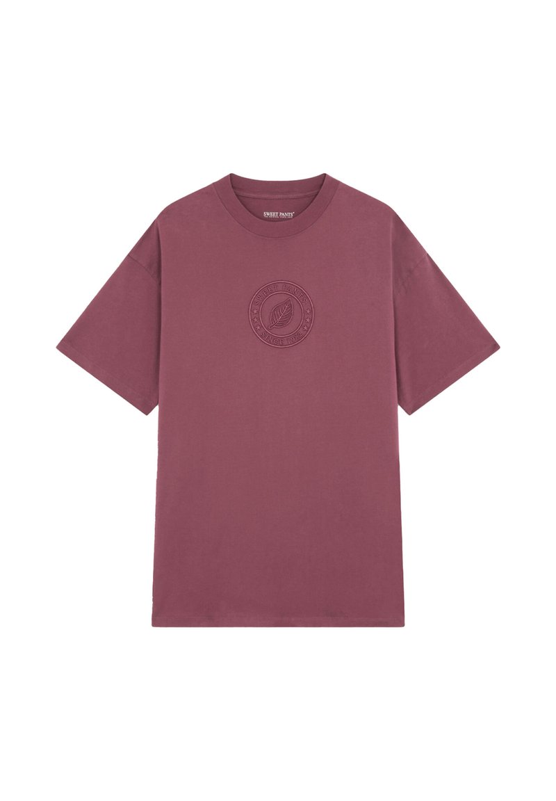 T-shirt en coton bordeaux avec un col rond et des manches courtes. Présente un design de logo texturé sur la poitrine, style minimaliste et décontracté.