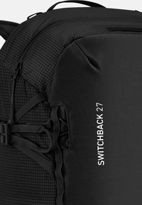Black backpack featuring a textured grid pattern, adjustable straps, and the text "SWITCHBACK 27" printed in white on the side.