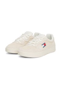 Zapatillas beige de ante con un acabado texturizado, cuentan con cordones blancos y un pequeño logotipo multicolor en el lateral.