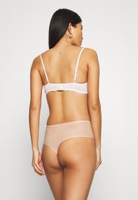 Bra in light pink with adjustable straps and a clasp back, paired with a smooth, nude-colored high-waisted panty.