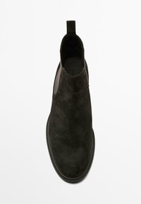 Stivale Chelsea in suede nero con pannelli elastici ai lati e linguetta, visto dall'alto su uno sfondo bianco.