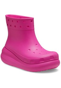 Zapato tipo clog de color rosa brillante, con punta redondeada, agujeros de ventilación en la parte superior y los laterales, y una suela gruesa y acolchada.