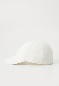 Boné de beisebol branco de algodão com aba curva, tecido texturizado e seis orifícios de ventilação. Apresenta um pequeno detalhe bordado na frente.