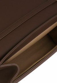 Braun ledernes Geldbörse mit Steppdetails und beigem Innenfutter, teilweise geöffnet gezeigt.
