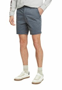 Grå bomulds shorts til mænd med klassisk pasform, der har sidelommer, knaplukning og opsmøg ved kanten, parret med hvide sneakers og lyse sokker.