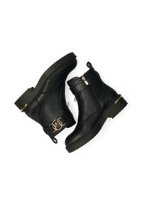 Botas de tobillo de cuero negro con puntera redondeada, cremalleras laterales y una hebilla dorada decorativa en la correa. Acabado texturizado, tacón bajo y cuadrado.