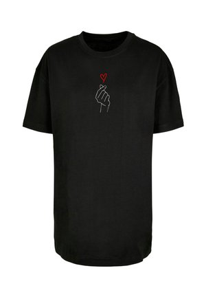 Zwarte katoenen t-shirt met korte mouwen; heeft een witte omtrek van een hand die een hartgebaar vormt en een klein rood hart erboven.