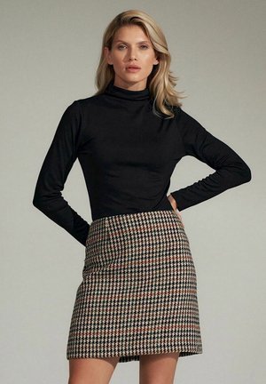 Czarny golf zestawiony z wężowym spódnicą w biało-czarną kratę w beżowych, brązowych i subtelnych czerwonych akcentach. Gładka tekstura materiału i dopasowany krój.