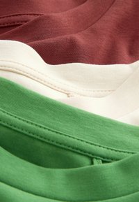Gros plan sur un tissu montrant les détails de la couture sur des couches de textile en coton marron, crème et vert.