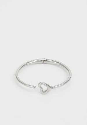 Ασημένιο βραχιόλι με σχέδιο σε σχήμα καρδιάς. Λείο μεταλλικό επιφάνεια με γυαλιστερό φινίρισμα και χωρίς επιπλέον διακοσμήσεις.