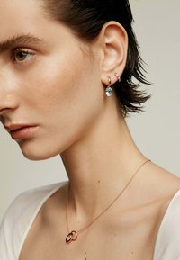 Los pendientes de oro rosa presentan una gran piedra de aguamarina y pequeños acentos en rosa, acompañados de un delicado collar de cadena de oro rosa.