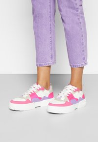 Sneakers chunky com uma mistura de materiais rosa, branco, lavanda e bege. Design com atacadores, sola texturizada e acentos de padrão geométrico.