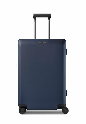 Valigia rigida blu scuro con quattro ruote e manico telescopico esteso, marchiata Porsche Design al centro anteriore.
