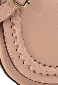 Roze leren handtas met gevlochten detail langs de rand, met zichtbare stiksels, een gladde textuur en een koperen sluiting.