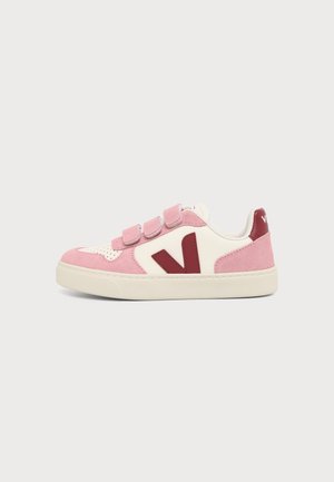 Sneaker basse en daim rose, cuir blanc, logo rouge "V" et trois bandes velcro roses sur le côté avec semelle écrue.