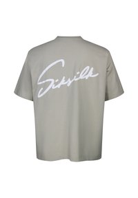 T-shirt gris clair à manches courtes avec un grand logo cursif blanc "SikSilk" imprimé dans le dos.