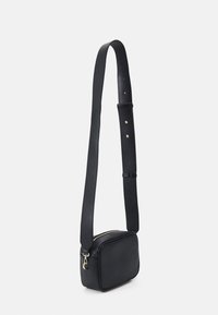 Borsa a tracolla nera in pelle con forma rettangolare. Presenta una zip dorata, una tracolla regolabile e una superficie testurizzata.