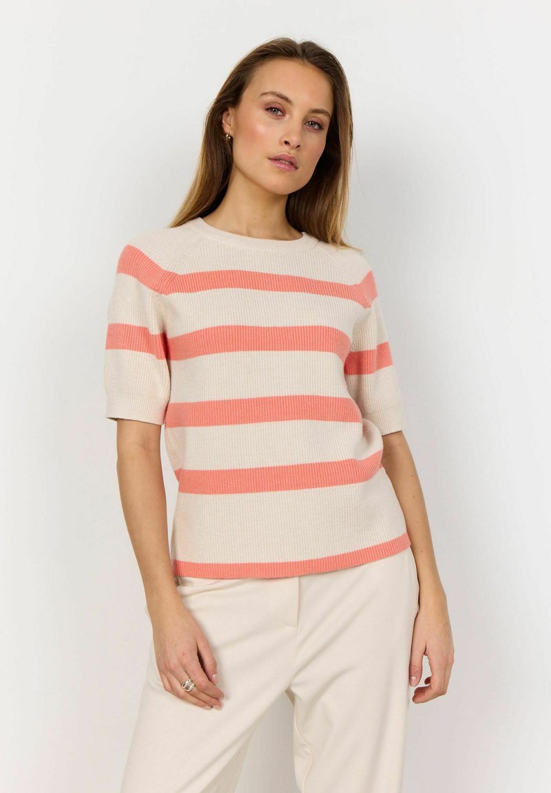 Striped short-sleeve sweater in beige and coral, featuring a ribbed texture and a crew neckline. Paired with cream-colored trousers.