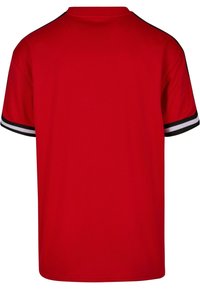 Tricou roșu cu mânecă scurtă, cu guler rotund, având accente cu dungi negre și albe pe mâneci. Fabricat din material respirabil.