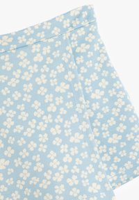 Tela azul con un patrón floral en blanco, con una textura suave y un borde rematado, que muestra pequeñas flores dispersas.