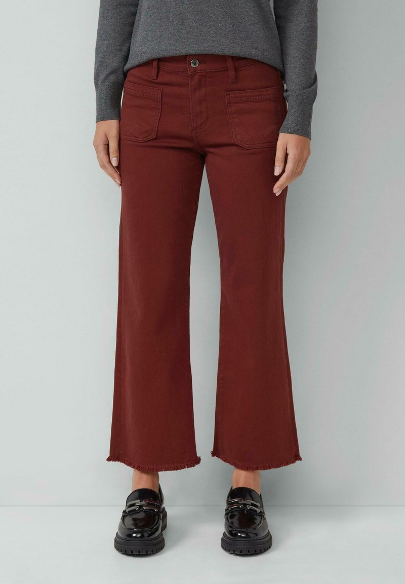 Rude kolorowe spodnie z szerokimi nogawkami i postrzępionymi brzegami, z kieszeniami z przodu i z tyłu. W połączeniu z czarnymi loafersami, które prezentują elegancki design.