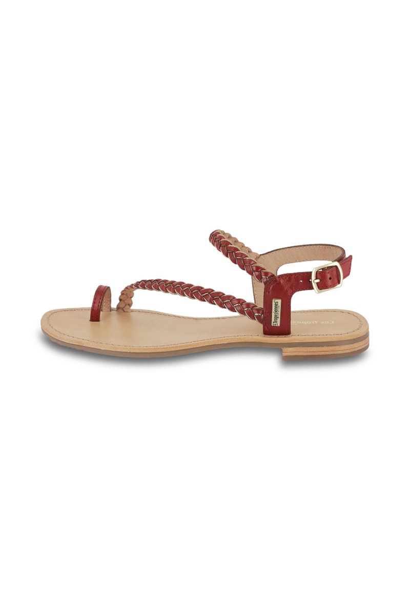 Sandalo rosso in pelle con design a fascia intrecciata, suola piatta e fibbia regolabile alla caviglia. Plantare color naturale con accenti minimi.