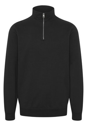 Pull noir à col zippé fabriqué dans un tissu doux et extensible. Il dispose d'un col haut, de manches longues et de poignets et d'un bas côtelés pour un ajustement confortable.