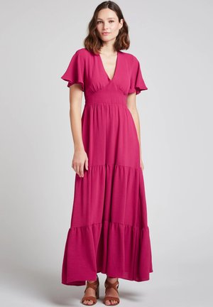 Robe longue fuchsia avec manches courtes à volant, col en V profond et jupe à volants, confectionnée dans un tissu léger à finition texturée.