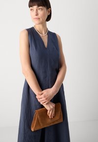 Marineblå lin kjole med V-hals, kombinert med en brun semsket skinn clutch. Kjolen har minimale sømdetaljer. Glatt tekstur gjennomgående.