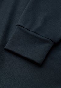 Dettaglio delle maniche di un pullover blu scuro, realizzato in tessuto testurizzato. Presenta un polsino aderente con una finitura liscia, evidenziando linee pulite e cuciture minime.