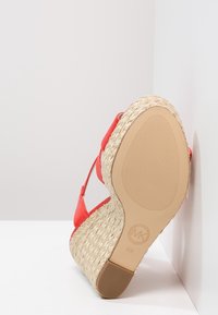 Sandalo rosso con tacco in juta intrecciata, suola in gomma e fasce in tessuto morbido. Presenta un fondo texturizzato per una migliore aderenza e un dettaglio con logo.