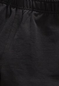 Tissu en mélange de coton noir avec une texture douce, présentant une taille élastique et des détails de couture lisses.