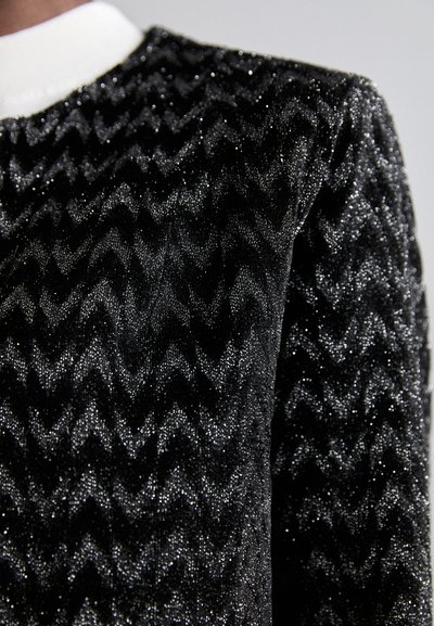 Black fabric with a zigzag pattern, featuring a sparkling texture. The collar is white. The material appears soft and textured.