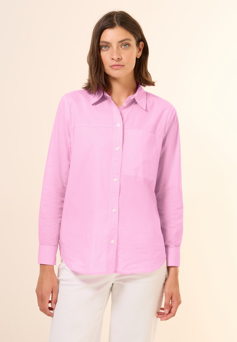 Camicia a maniche lunghe di un delicato rosa pallido, con colletto classico e un dettaglio di tasca frontale, realizzata in un tessuto leggero e morbido.