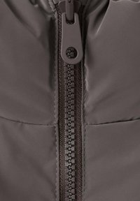 Giubbotto imbottito in materiale marrone scuro, con una chiusura centrale a zip dotata di un gancio rotondo e una delicata texture trapuntata.