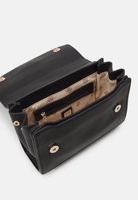 Sac à main en cuir texturé noir avec ferrures dorées. L'intérieur présente une doublure beige avec un motif de logo, incluant une poche zippée pour l'organisation.