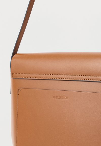 Τσάντα ώμου από δέρμα σε ταμπά απόχρωση με λείο φινίρισμα, εμφανείς ραφές και μπροστινή τσέπη με ανάγλυφη επιγραφή «By Malene Birger».