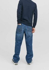Blå denimjeans med en avslappnad passform, med två bakfickor och en enkel midja. Matchas med en marinblå sweatshirt och sneakers.