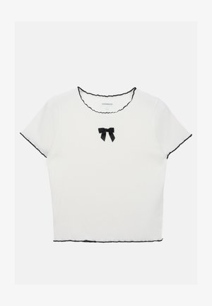 Valge lühikeste varrukatega topp, millel on must sakiline kaelus ja mansetid. Ees on väike must lipsu aksent.