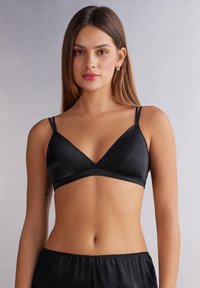 Svart satängbralette med V-ringning, tunna justerbara remmar och ett brett underband. Slät textur och minimalistisk stil.