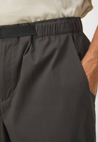 Stretchshorts med høy midje i mørkegrått, laget av lett materiale. Har sidelommer og subtil ribbet tekstur. Holdbar søm er synlig.