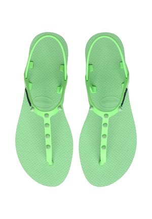 Zielone gumowe klapki z teksturowaną wkładką, regulowanymi paskami i okrągłymi guzikami do regulacji rozmiaru. Lekka i minimalistyczna konstrukcja.