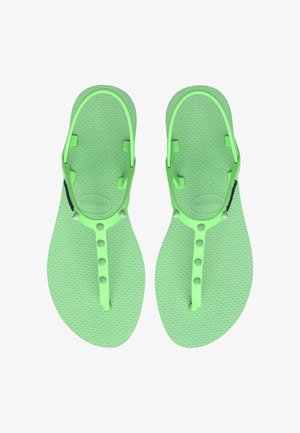 Zielone gumowe klapki z teksturowaną wkładką, regulowanymi paskami i okrągłymi guzikami do regulacji rozmiaru. Lekka i minimalistyczna konstrukcja.