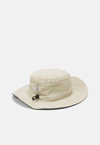 Vaalean beige leveälierinen hattu, jossa on verkkohihna, säädettävä naru ja kiinteä alapuoli, suunniteltu auringon suojaksi ja hengittävyydeksi.