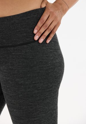 Zwarte sportleggingen met een gestructureerde afwerking en een brede tailleband, met vlakke naden en zonder zichtbare logo's of patronen.